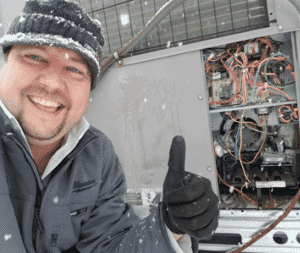 Dalco HVAC technician at outside electrical panel in the snow outside a Denver area home