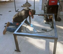 AC technician welding frame for air conditioner installation