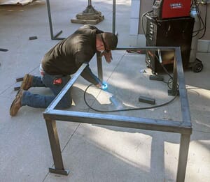 AC technician welding frame for air conditioner installation