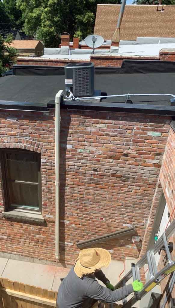 DALCO tech climbing ladder to perform AC maintenance on roof of Denver home