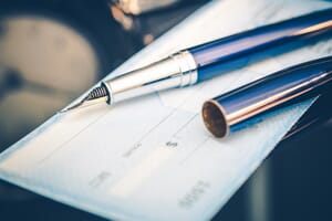 Pen lying on top of checkbook. Payment by checking, credit card and debit card are some of the finance options available with Dalco Heating & Air in Denver area.